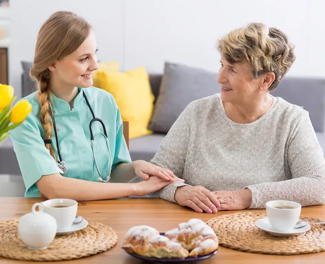 Carer and older woman having tea at the kitchen table