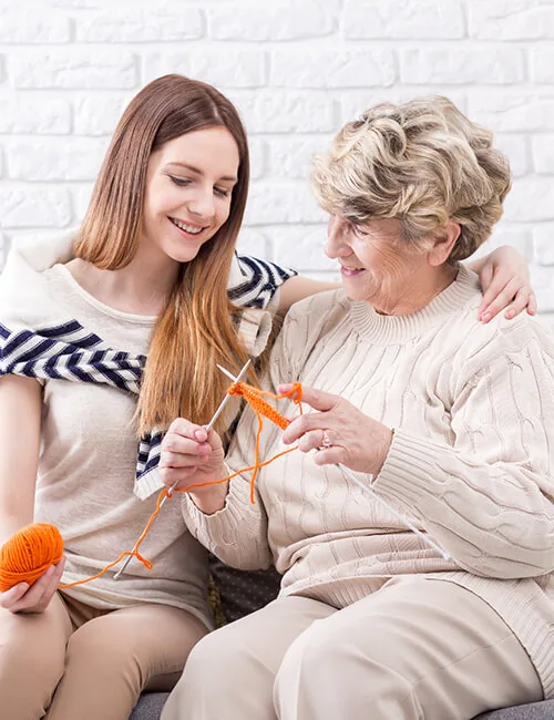 Carer and older woman knitting on the sofa