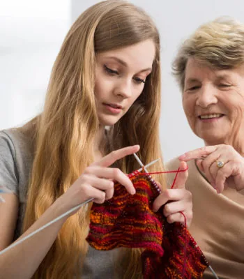 Carer and older woman knitting together