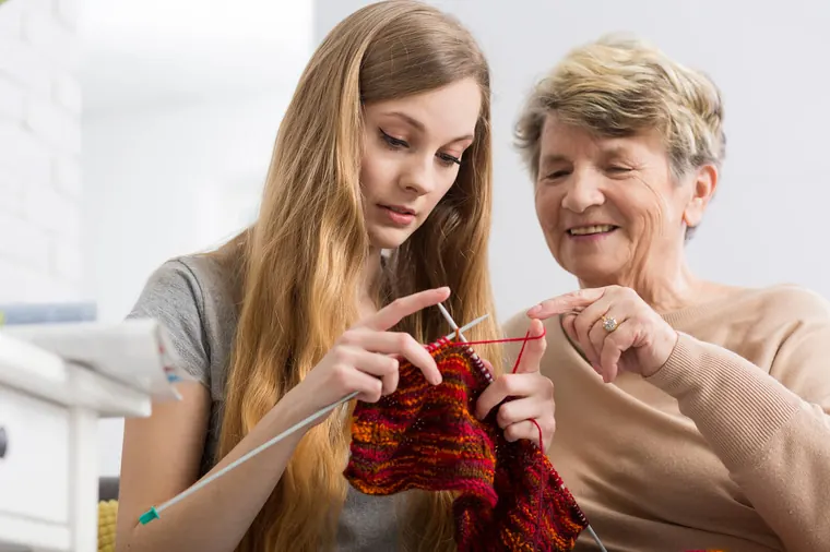 Carer and older woman knitting together at home