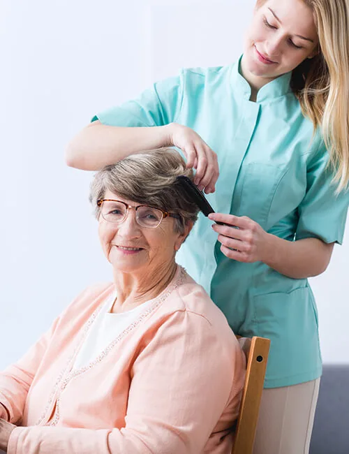 Carer brushing an older woman's hair
