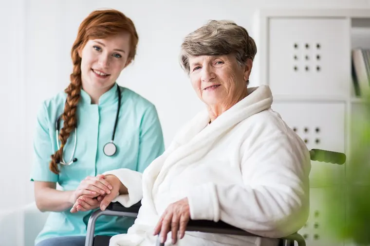 Carer supporting an older woman at home